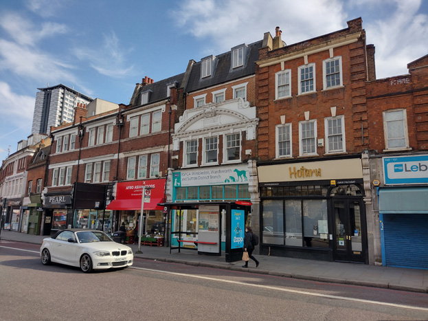 Fig. 55: Nos.141-143 (odd) Wandsworth High Street is a fine Edwardian Baroque refronting of an older building in dark red brick and ashlar. The building, formerly a bank, has a segmental pediment of ashlar with a cartouche bearing the date 1914 and the name David Greis. The adjoining 147-155 Wandsworth High Street (and probably Nos. 157-161 also) were completed by A. Edwin Westerman around 1932 in a neo-Georgian style. They are fronted in red brick with ashlar dressings and brick quoins.