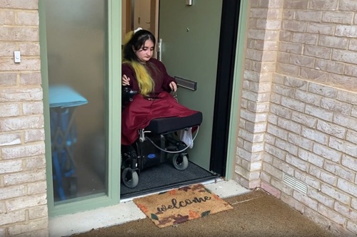 Amna uses the automated door entry system to access her home using her electric wheelchair