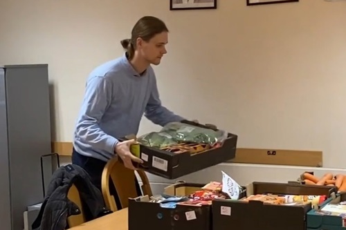 Pavlo carries vegetables as part of food bank volunteering