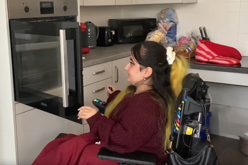 Amna opens the oven door in her fully accessible kitchen